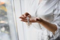 Beautiful bride in white wedding dress puts on earring. Beauty model girl is wearing jewelry. Female portrait in bridal gown for