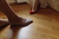 Beautiful bride in white wedding dress putting on red shoes, leg Royalty Free Stock Photo