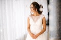 Beautiful bride in white wedding dress is standing in bright room and smiling Royalty Free Stock Photo