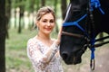 Beautiful bride in a white wedding dress stroking a horse, portrait of a blonde woman with a black stallion, wedding day Royalty Free Stock Photo