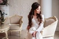 Beautiful bride in a white wedding peignoir in a morning.