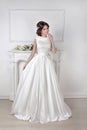 Beautiful bride woman posing in magnificent dress over white wall at modern interior Royalty Free Stock Photo