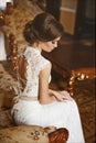 Beautiful bride, young model brunette woman, in stylish wedding dress with naked back sits on the vintage sofa and posing in luxur Royalty Free Stock Photo