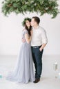 Beautiful bridesmaid with handsome groomsman in the studio hugging.