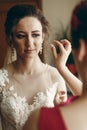 Beautiful bridesmaid helping brunette bride in white wedding dress put on luxury earrings, morning wedding preparation, bride with Royalty Free Stock Photo