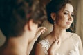 Beautiful bridesmaid helping brunette bride in white wedding dress put on luxury earrings, morning wedding preparation, bride with Royalty Free Stock Photo