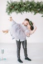 Beautiful bridesmaid in pine wreath and gray blue dress with handsome groomsman in the studio dancing.