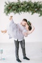 Beautiful bridesmaid in pine wreath and gray blue dress with handsome groomsman in the studio dancing.