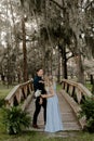 Beautiful Bridesmaid Woman in Blue Dress and Bouquet with Her Date at a Formal Wedding Party Celebration Event Outside in the Wood