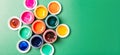 Beautiful, bright, mother-of-pearl, multicolored open cans of paint on a bright green background. The concept of creativity