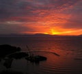 A beautiful bright red sunset. The sun goes behind the river and beyond the mountains Royalty Free Stock Photo