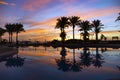 Beautiful bright sunrise reflected in the pool among palm trees Royalty Free Stock Photo