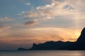 Beautiful bright sunset on the Black Sea in the Sudak. Seaside with outline of cape Kapchik. Crimea landscape. Royalty Free Stock Photo