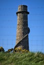 Beautiful bright vertical view of Ballycorus lead mining and smelting chimney tower seen through wire fence, Ballycorus