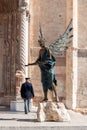 Beautiful bronze sculpture in front of the Veronese cathedral, a policeman walking by