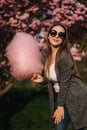 Beautiful brown hair model hold a cotton candy in hands and give a kiss. Young woman with pink cotton candy Royalty Free Stock Photo