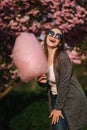 Beautiful brown hair model hold a cotton candy in hands and give a kiss. Young woman with pink cotton candy Royalty Free Stock Photo