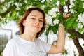 Beautiful brown haired woman in an apple orchard sniffing blooming flowers Royalty Free Stock Photo