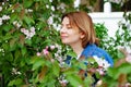 Beautiful brown haired woman with blue eyes in an Apple orchard sniffing blooming flowers Royalty Free Stock Photo