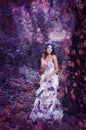 Beautiful brown-haired woman in a long white dress, with a wreath of lavender on her head, is in the fairy forest. Royalty Free Stock Photo