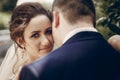 Beautiful brunette bride portrait face close-up, sensual groom kissing hugging bride, newlywed couple posing outdoors in park Royalty Free Stock Photo