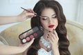 Beautiful brunette bride wedding portrait with makeup and hairstyle. Red lips and manicure nails. Stylist makes make-up model on Royalty Free Stock Photo