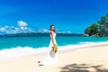 beautiful brunette bride in white wedding dress with big long white train and with wedding bouquet stand on shore sea Royalty Free Stock Photo