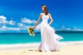 beautiful brunette bride in white wedding dress with big long white train and with wedding bouquet stand on shore sea Royalty Free Stock Photo