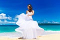 beautiful brunette bride in white wedding dress with big long white train and with wedding bouquet stand on shore sea Royalty Free Stock Photo