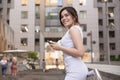 Beautiful brunette business woman in grey smark casual dress working on a mobile phone in her hands outdoors. European city on Royalty Free Stock Photo