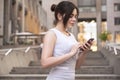 Beautiful brunette business woman in grey smark casual dress working on a mobile phone in her hands outdoors. European city on Royalty Free Stock Photo