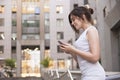 Beautiful brunette business woman in grey smark casual dress working on a mobile phone in her hands outdoors. European city on Royalty Free Stock Photo