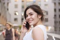 Beautiful brunette business woman in grey smark casual dress working on a mobile phone in her hands outdoors. European city on Royalty Free Stock Photo