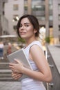 Beautiful brunette business woman in grey smark casual dress working on a tablet in her hands outdoors. European city on Royalty Free Stock Photo