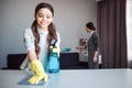 Beautiful brunette caucasian mother and daughter cleaning together in room. Girl hold spray in hands and clean table