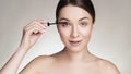 Beautiful brunette caucasian young woman prepare herself, applying mascara on her eyes with a brush. Clean, fresh, natural, Royalty Free Stock Photo