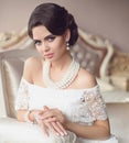 Beautiful brunette, elegant woman portrait. Fashion pearl jewelry set. Retro lady with makeup, wavy hairstyle in white dress
