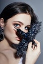 Beautiful brunette girl with big blue eyes holding a black brooch decoration in the form of birds. Fashion portrait natural Royalty Free Stock Photo