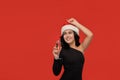 Beautiful brunette girl in a black dress and Santa hat dancing holding glass of champagne. Royalty Free Stock Photo