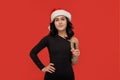 Beautiful brunette girl in a black dress and Santa hat holding glass of champagne. Royalty Free Stock Photo