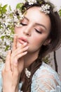 Beautiful brunette girl in blue dress with a gentle romantic make-up, pink lips and flowers. The beauty of the face. Royalty Free Stock Photo