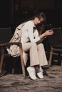 beautiful brunette girl dressed in white blouse, pants, sneakers with a handbag and camel coat in hands. Stylish trendy Royalty Free Stock Photo