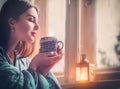 Beautiful brunette girl drinking coffee at home, looking out the window. Beauty model woman with cup of hot tea Royalty Free Stock Photo