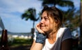 Beautiful brunette girl enjoys warm sunny weather on the beach at the park and thinks about future, life goals and travel plans Royalty Free Stock Photo