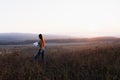 Beautiful brunette girl in glasses dressed in casual clotehs walks among the meadow and reading a book, colorful forest Royalty Free Stock Photo