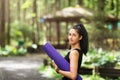 A beautiful brunette girl with a gymnastic mat poses against the background of a yoga house Royalty Free Stock Photo