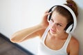 Beautiful brunette girl with headphones listening to music while sitting on the floor in an empty room on the white wall Royalty Free Stock Photo