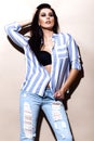 Beautiful brunette girl in jeans and striped shirt posing in studio. Royalty Free Stock Photo