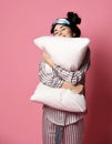 Beautiful brunette girl just woke up and hugging soft pillow. Woman yawning smiling sleepy day on pink Royalty Free Stock Photo