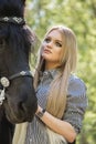 Beautiful brunette girl with long hair posing with a red horse in forest Royalty Free Stock Photo